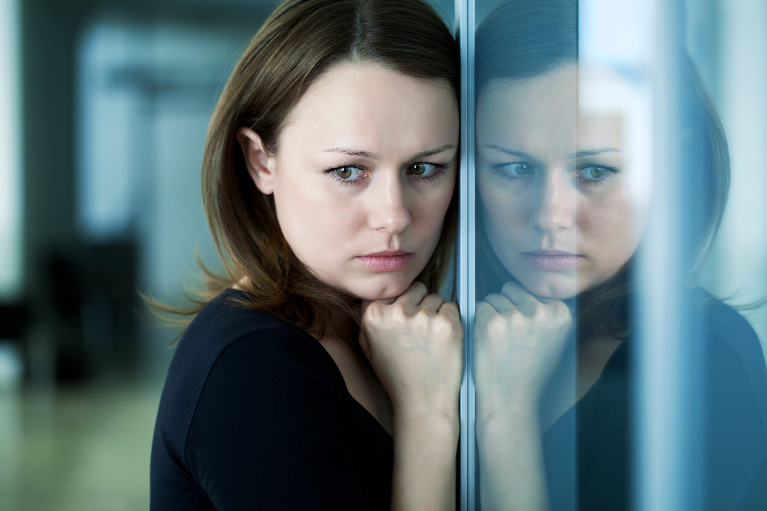 young woman woman leaned against glass wall in crisis moment